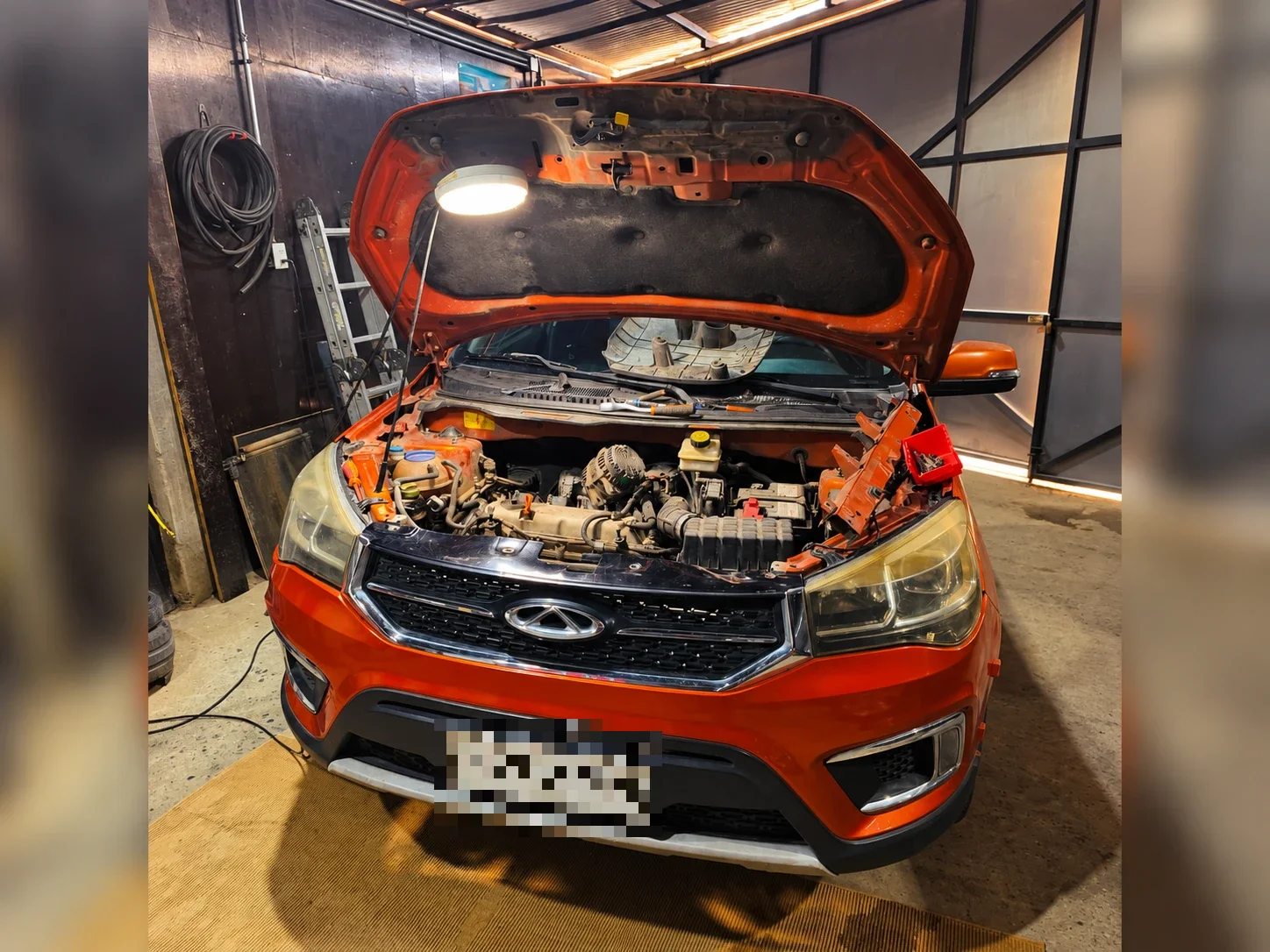 Auto naranjo con el capó abierto durante una revisión en el taller